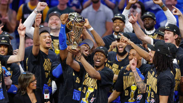 Oklahoma City, Oklahoma, USA; Oklahoma City Thunder forward Jalen Williams (8) holds up the Bill Russell NBA Finals MVP trophy after winner Oklahoma City Thunder guard Shai Gilgeous-Alexander hands it to him at the end of Game 7 of the 2025 NBA Finals against the Indiana Pacers at Paycom Center. Mandatory Credit: Alonzo Adams-Imagn Images