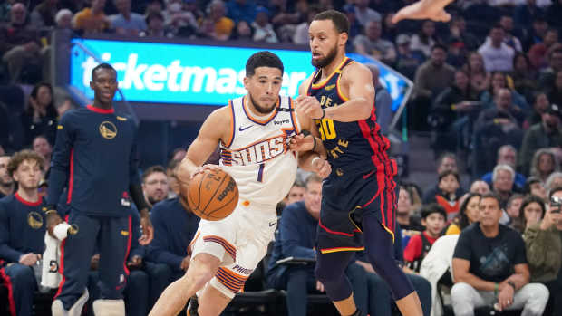 San Francisco, California, USA; Phoenix Suns guard Devin Booker (1) dribbles next to Golden State Warriors guard Stephen Curry (30) in the first quarter at the Chase Center. Mandatory Credit: Cary Edmondson-Imagn Images