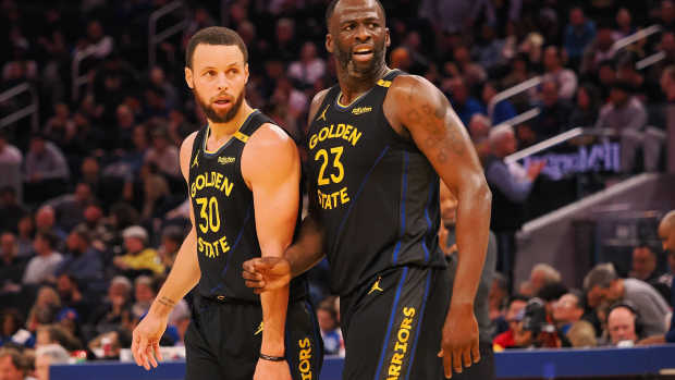 Golden State Warriors guard Stephen Curry (30) and forward Draymond Green (23) look towards an Orlando Magic player at half time at Chase Center.