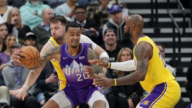 Utah Jazz forward John Collins (20) tries to keep the ball away from Los Angeles Lakers guard Luka Doncic (77) and forward LeBron James (23) during the first quarter at Delta Center. Mandatory Credit: Chris Nicoll-Imagn Images