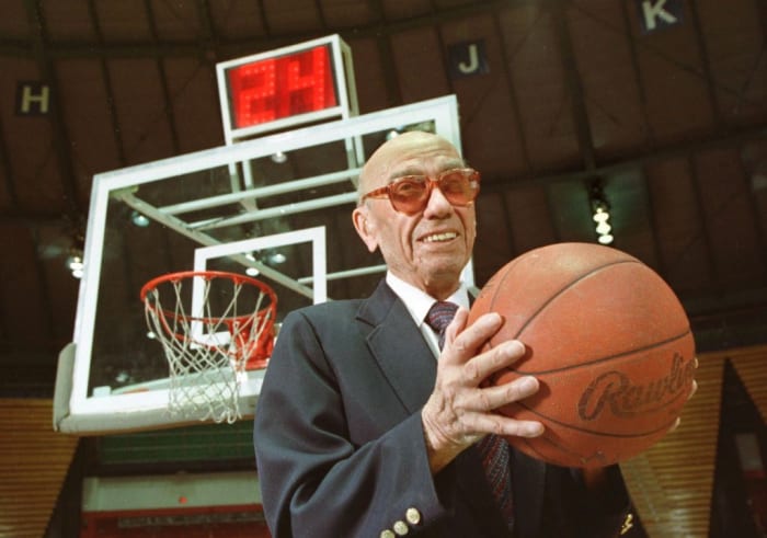 The late Danny Biasone, an innovator of the 24-second shot clock for professional basketball, is shown in this March 8, 1992 photograph at a gym at Syracuse University in Syracuse, N.Y. Behind him is a modern shot clock. Biasone and other National Basketball Association owners met in Syracuse in 1954 and tested the 24-second clock at a basketball game in a local school. That decaying school now is reaching out to the NBA for a donation. (AP Photo/Michael Okoniewski)