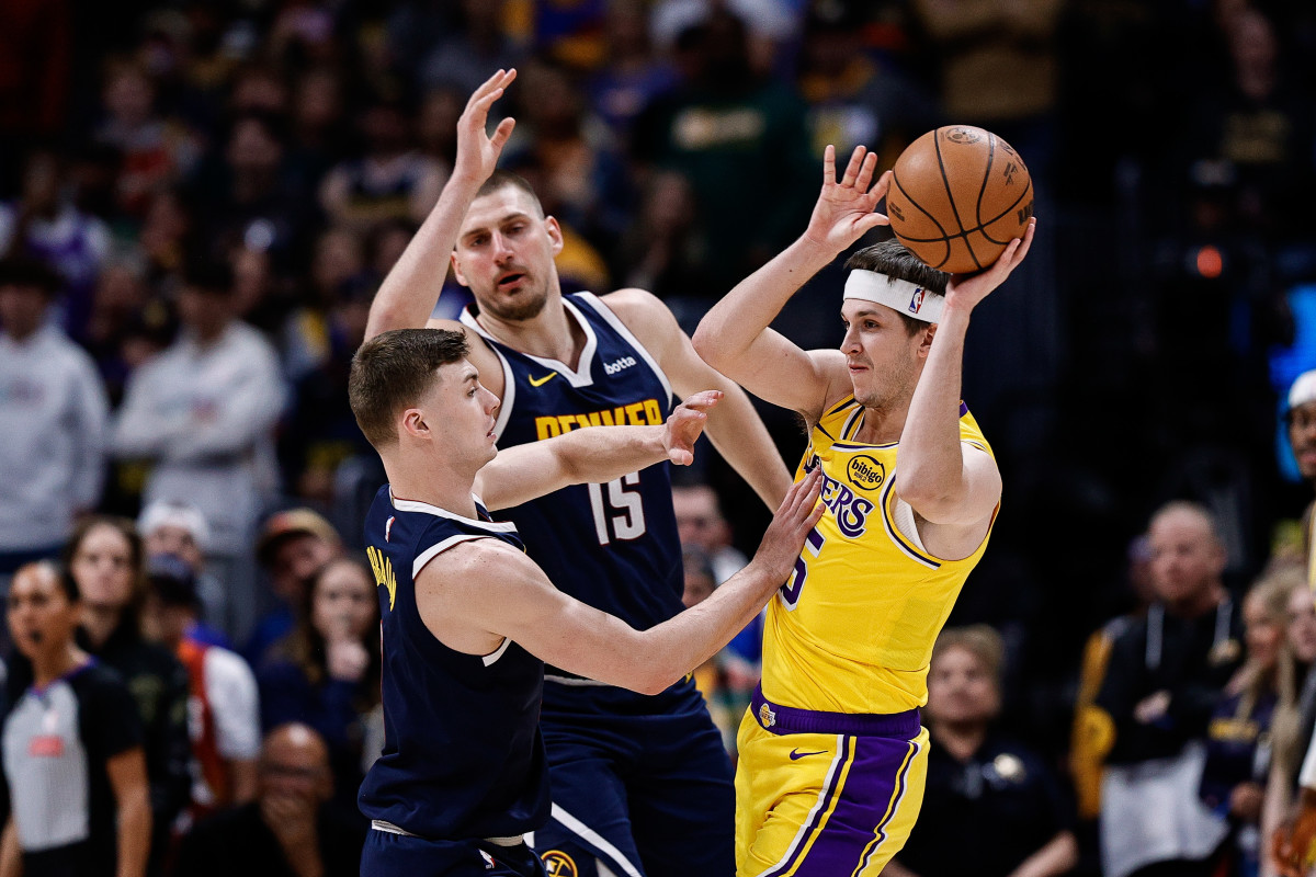 Mar 14, 2025; Denver, Colorado, USA; Los Angeles Lakers guard Austin Reaves (15) passes the ball under pressure from Denver Nuggets guard Christian Braun (0) and center Nikola Jokic (15) in the first quarter at Ball Arena. Mandatory Credit: Isaiah J. Downing-Imagn Images