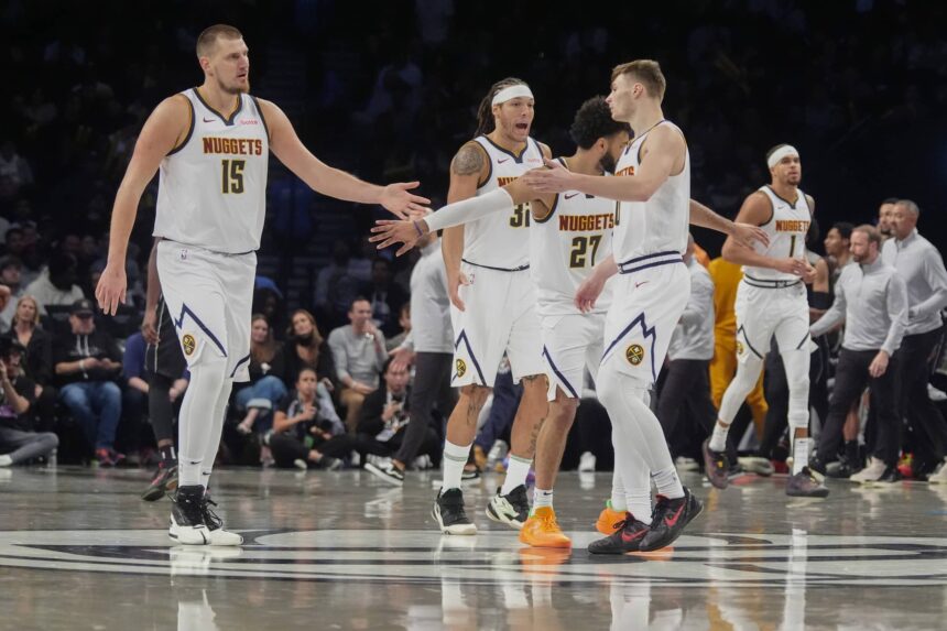 Denver Nuggets center Nikola Jokic (15), point guard Jamal Murray (27) and guard Christian Braun (0) celebrate a play on the court against the Brooklyn Nets during overtime at Barclays Center.