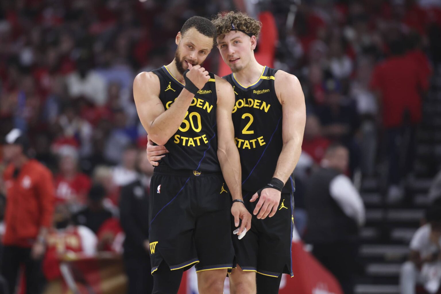 Warriors guard Stephen Curry and guard Brandin Podziemski talk during a timeout during game seven of first round for the 2025 NBA Playoffs against the Rockets at Toyota Center.