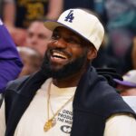 Lakers forward LeBron James, wearing a Los Angeles Dodgers hat, smiles after watching his son, guard Bronny James, dunk a rebound against the Warriors in the third quarter at Chase Center