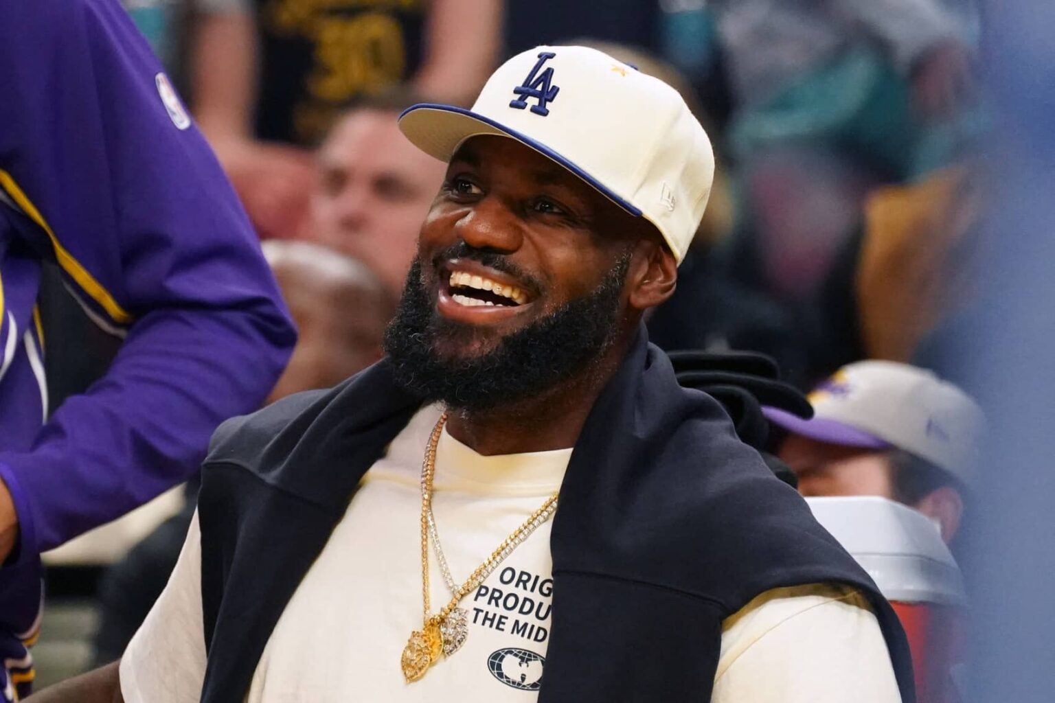 Lakers forward LeBron James, wearing a Los Angeles Dodgers hat, smiles after watching his son, guard Bronny James, dunk a rebound against the Warriors in the third quarter at Chase Center