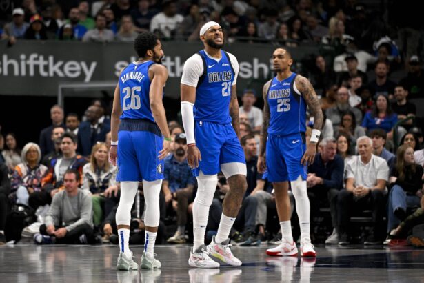 Mar 31, 2025; Dallas, Texas, USA; Dallas Mavericks guard Spencer Dinwiddie (26) and forward P.J. Washington (25) check on center Daniel Gafford (21) during the second half against the Brooklyn Nets at the American Airlines Center. Mandatory Credit: Jerome Miron-Imagn Images