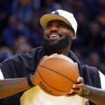 Oct 5, 2025; San Francisco, California, USA; Los Angeles Lakers forward LeBron James (23), wearing a Los Angeles Dodgers hat, watches from the sideline during a break against the Golden State Warriors in the third quarter at Chase Center. Mandatory Credit: David Gonzales-Imagn Images