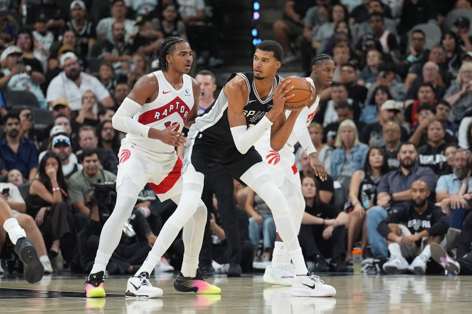 Oct 27, 2025; San Antonio, Texas, USA; San Antonio Spurs forward/center Victor Wembanyama (1) looks to pass in front of Toronto Raptors forward Collin Murray-Boyles (12) in the second half at Frost Bank Center. Mandatory Credit: Daniel Dunn-Imagn Images
