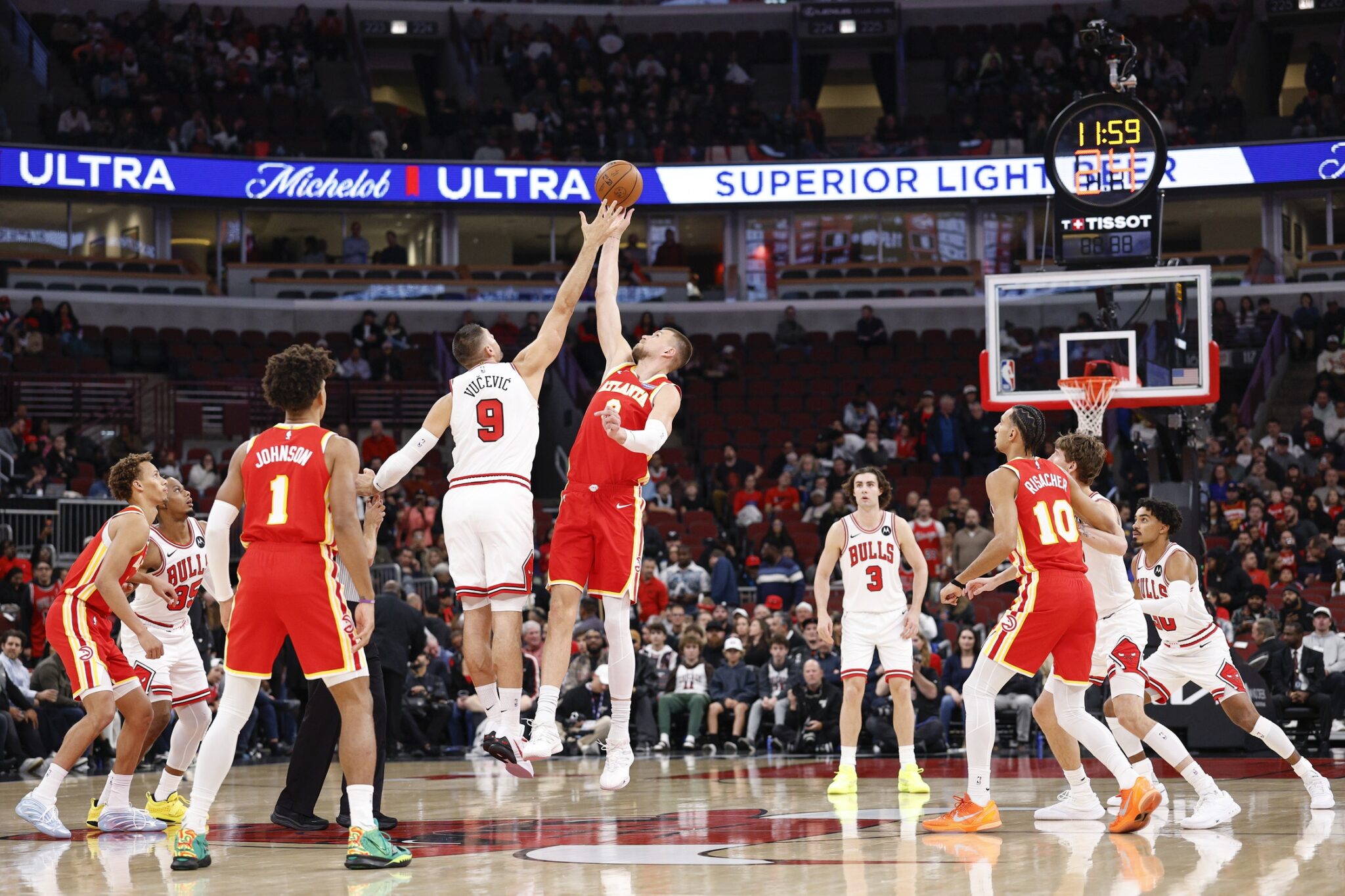Oct 27, 2025; Chicago, Illinois, USA; Chicago Bulls center Nikola Vucevic (9) battles for the ball with Atlanta Hawks center Kristaps Porzingis (8) at the tip-off of an NBA game at United Center. Mandatory Credit: Kamil Krzaczynski-Imagn Images