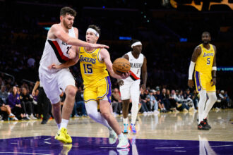 Oct 27, 2025; Los Angeles, California, USA; Los Angeles Lakers guard Austin Reaves (15) drives the ball under pressure from Portland Trail Blazers center Donovan Clingan (23) during the second half at Crypto.com Arena. Mandatory Credit: William Liang-Imagn Images