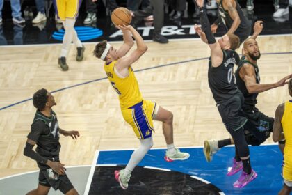 Oct 29, 2025; Minneapolis, Minnesota, USA; Los Angeles Lakers guard Austin Reaves (15) shoots a game winning shot over Minnesota Timberwolves guard Donte DiVincenzo (0) in the second half at Target Center. Mandatory Credit: Jesse Johnson-Imagn Images