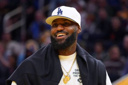 San Francisco, California, USA; Los Angeles Lakers forward LeBron James (23), wearing a Los Angeles Dodgers hat, watches from the sideline during a break against the Golden State Warriors in the third quarter at Chase Center. Mandatory Credit: David Gonzales-Imagn Images
