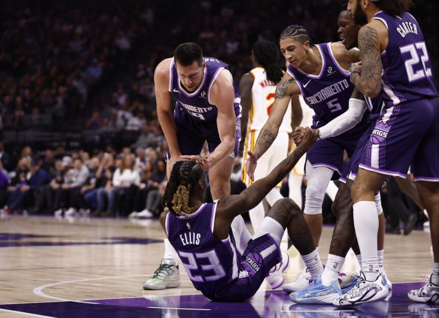 Nov 12, 2025; Sacramento, California, USA; Sacramento Kings teammates help up guard Keon Ellis (23) after drawing an offensive foul against the Atlanta Hawks during the first quarter at Golden 1 Center. Mandatory Credit: Kelley L Cox-Imagn Images
