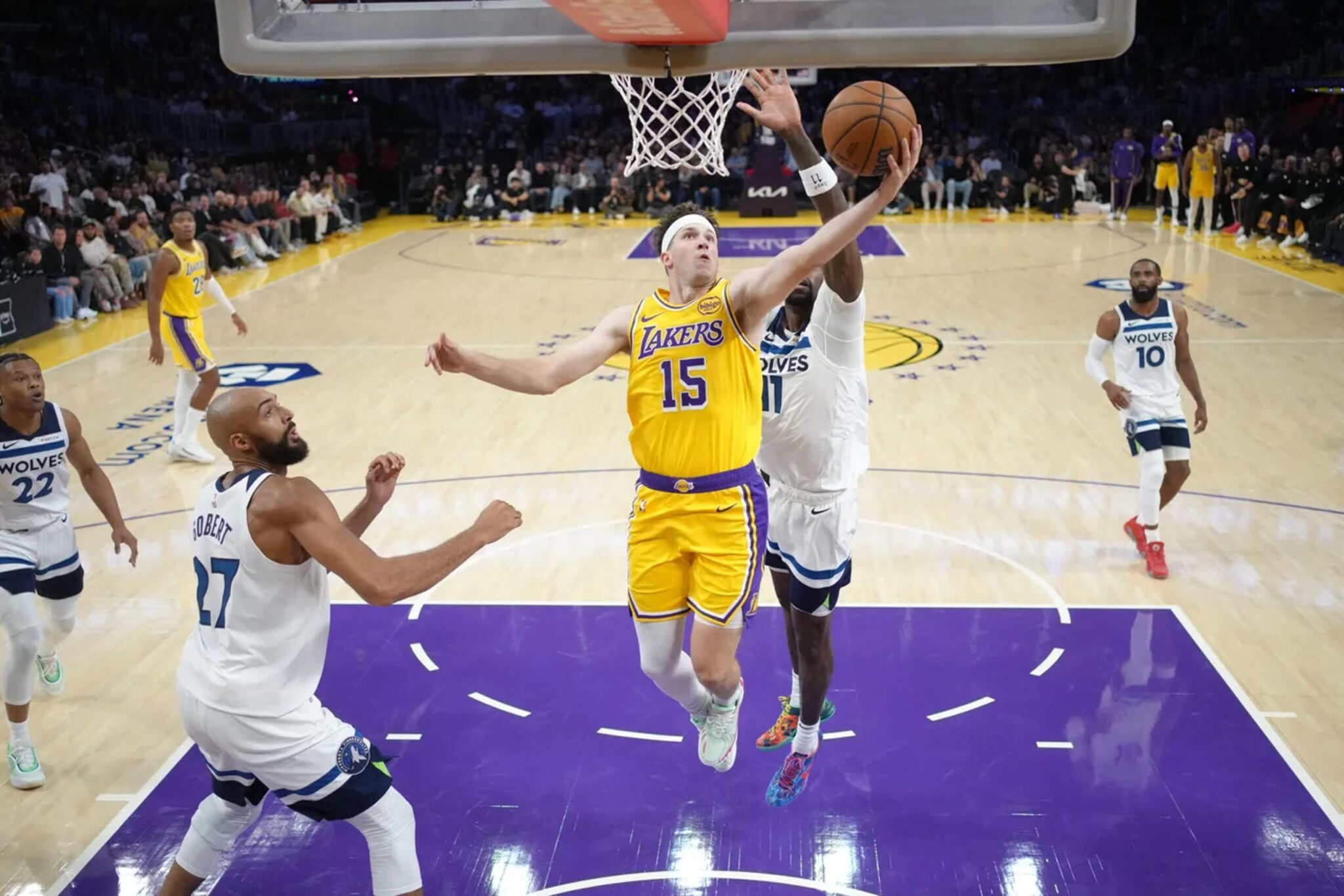 Oct 24, 2025; Los Angeles, California, USA; Los Angeles Lakers guard Austin Reaves (15) shoots the ball against Minnesota Timberwolves center Rudy Gobert (27) and center Naz Reid (11) in the first half at Crypto.com Arena. Mandatory Credit: Kirby Lee-Imagn Images