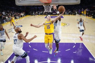 Oct 24, 2025; Los Angeles, California, USA; Los Angeles Lakers guard Austin Reaves (15) shoots the ball against Minnesota Timberwolves center Rudy Gobert (27) and center Naz Reid (11) in the first half at Crypto.com Arena. Mandatory Credit: Kirby Lee-Imagn Images