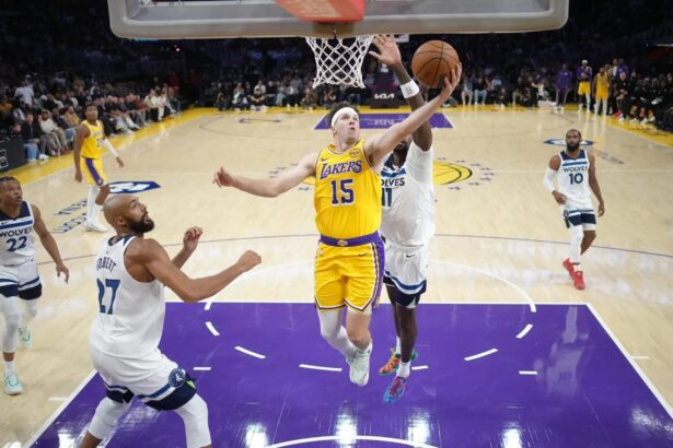 Oct 24, 2025; Los Angeles, California, USA; Los Angeles Lakers guard Austin Reaves (15) shoots the ball against Minnesota Timberwolves center Rudy Gobert (27) and center Naz Reid (11) in the first half at Crypto.com Arena. Mandatory Credit: Kirby Lee-Imagn Images