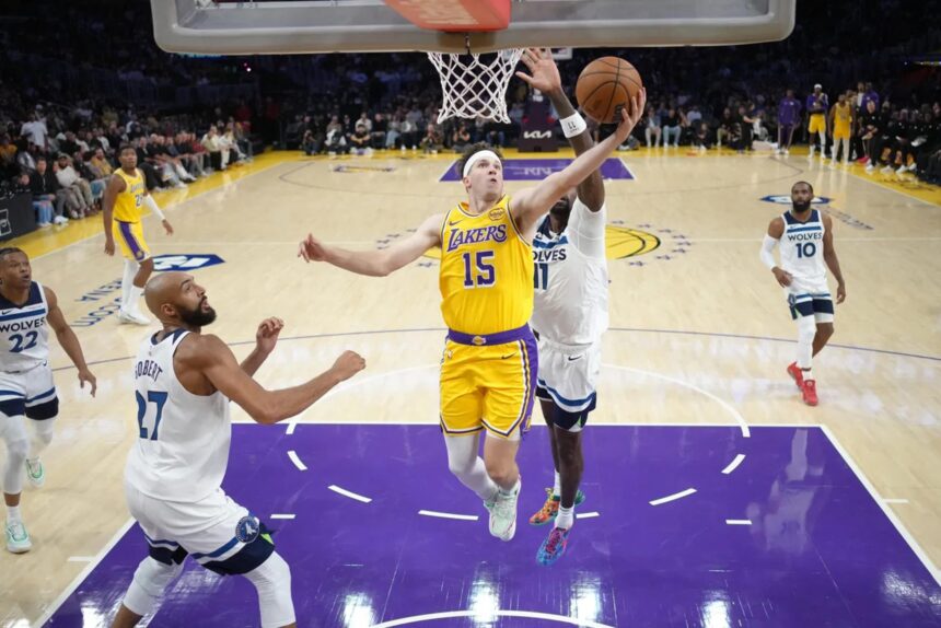 Oct 24, 2025; Los Angeles, California, USA; Los Angeles Lakers guard Austin Reaves (15) shoots the ball against Minnesota Timberwolves center Rudy Gobert (27) and center Naz Reid (11) in the first half at Crypto.com Arena. Mandatory Credit: Kirby Lee-Imagn Images