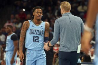 Nov 7, 2025; Memphis, Tennessee, USA; Memphis Grizzlies guard Ja Morant (12) shakes hands with head coach Tuomas Iisalo (obscured) during a substitution in the first quarter against the Dallas Mavericks at FedExForum. Mandatory Credit: Petre Thomas-Imagn Images
