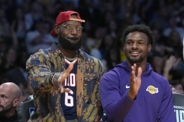 Los Angeles Lakers forward LeBron James (left) and son Bronny James watch from the bench in the second half against the Minnesota Timberwolves at Crypto.com Arena.