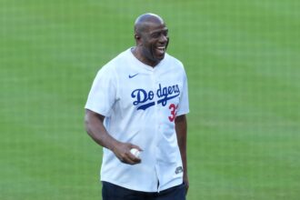 Los Angeles Dodgers co owner Magic Johnson reacts before throwing the ceremonial first pitch before game five of the 2025 MLB World Series between the Toronto Blue Jays and the Los Angeles Dodgers at Dodger Stadium.