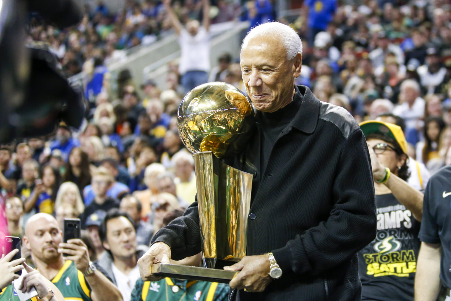 Oct 5, 2018; Seattle, WA, USA; Former Seattle Supersonics head coach Lenny Wilkens holds the 1979 championship trophy during a third quarter timeout of a game between the Sacramento Kings and Golden State Warriors at KeyArena. Mandatory Credit: Joe Nicholson-Imagn Images