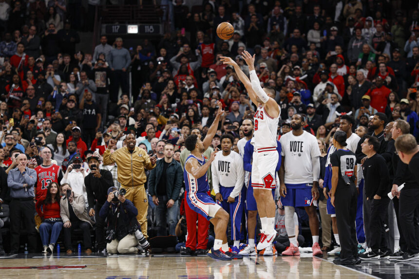 Nov 4, 2025; Chicago, Illinois, USA; Chicago Bulls center Nikola Vucevic (9) shoots and scores a game winning three-pointer against Philadelphia 76ers guard Quentin Grimes (5) during the second half at United Center. Mandatory Credit: Kamil Krzaczynski-Imagn Images