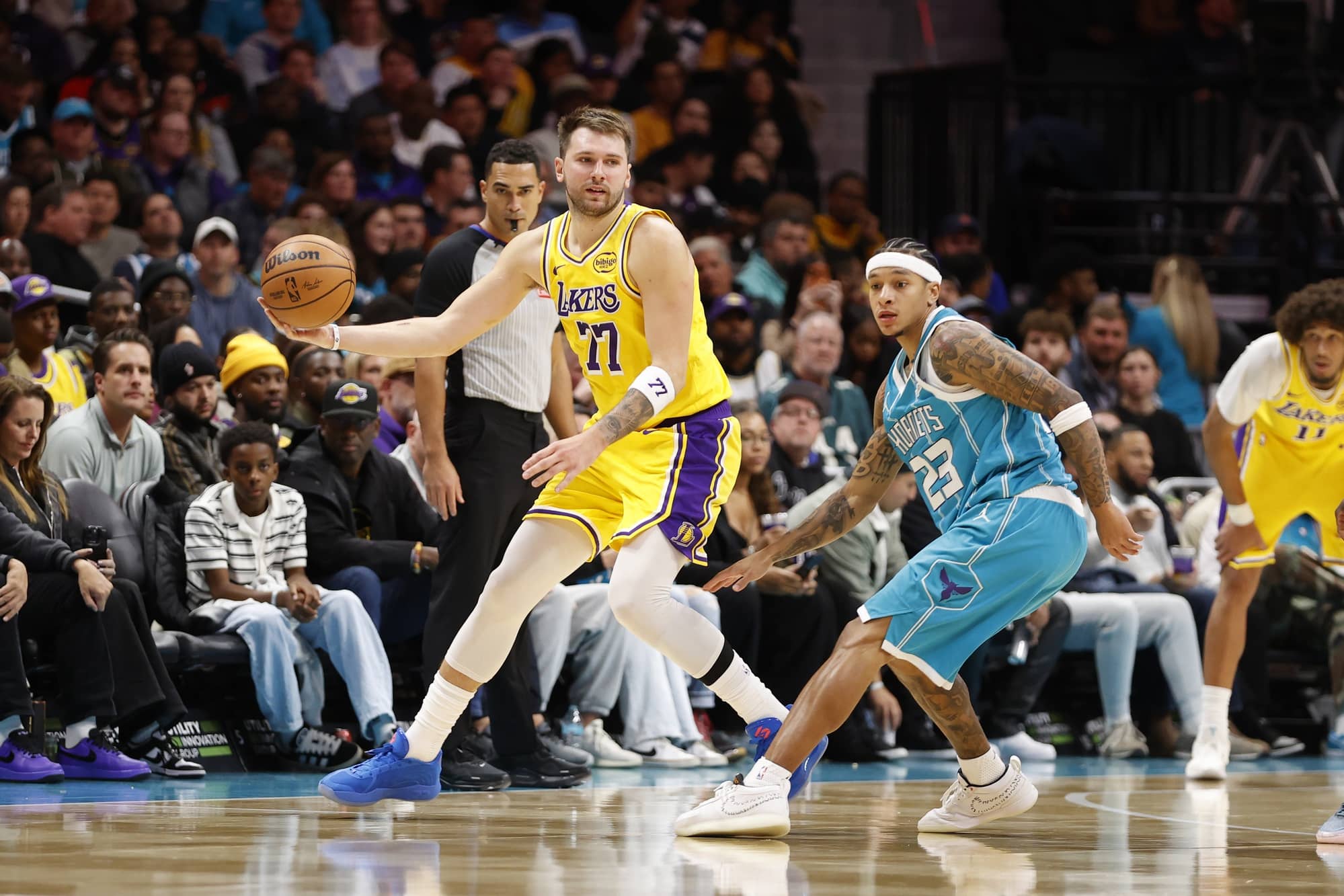 Nov 10, 2025; Charlotte, North Carolina, USA; Los Angeles Lakers forward/guard Luka Doncic (77) keeps the ball away from Charlotte Hornets guard Tre Mann (23) during the second half at Spectrum Center. Mandatory Credit: Brian Westerholt-Imagn Images