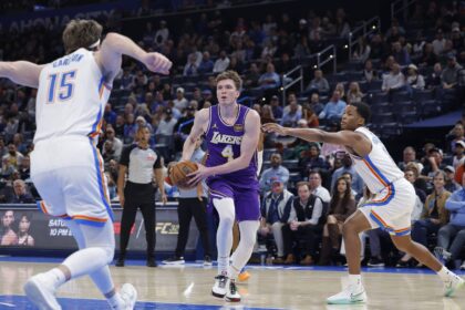 Nov 12, 2025; Oklahoma City, Oklahoma, USA; Los Angeles Lakers forward Dalton Knecht (4) drives to the basket between Oklahoma City Thunder center Branden Carlson (15) and guard Chris Youngblood (3) during the fourth quarter at Paycom Center. Mandatory Credit: Alonzo Adams-Imagn Images