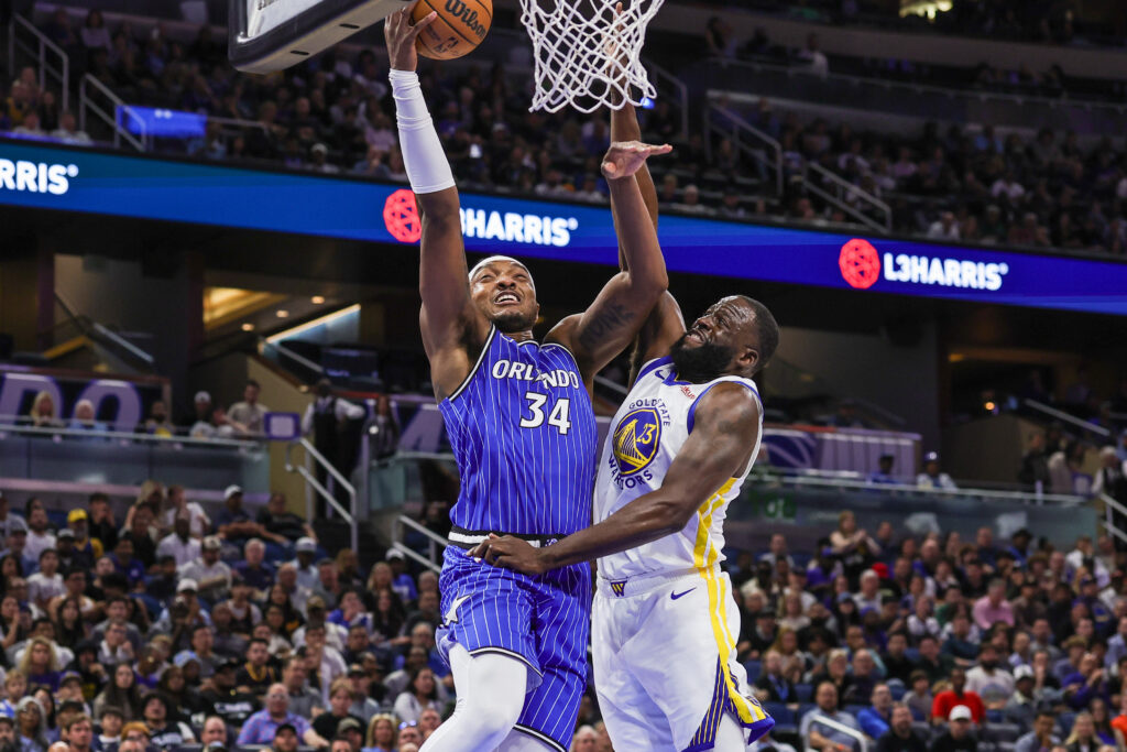 Nov 18, 2025; Orlando, Florida, USA; Orlando Magic center Wendell Carter Jr. (34) goes to the basket against Golden State Warriors forward Draymond Green (23) during the first quarter at Kia Center. Mandatory Credit: Mike Watters-Imagn Images