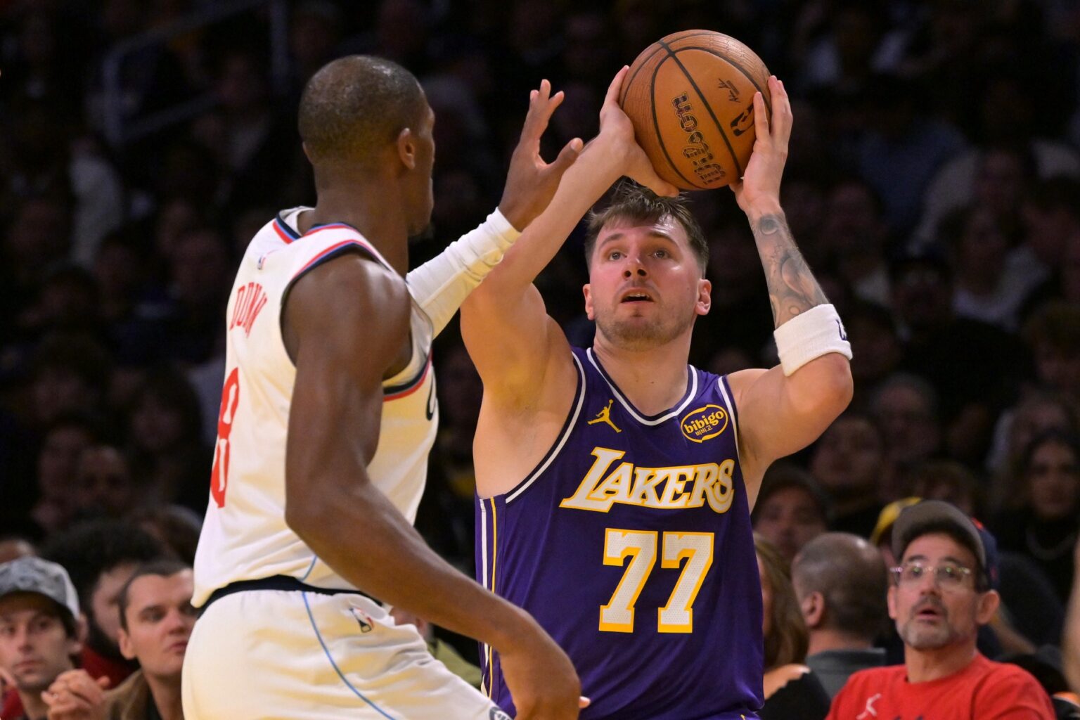 Nov 25, 2025; Los Angeles, California, USA; Los Angeles Lakers guard Luka Doncic (77) is defended by Los Angeles Clippers guard Kris Dunn (8) during the first half at Crypto.com Arena. Mandatory Credit: Jayne Kamin-Oncea-Imagn Images