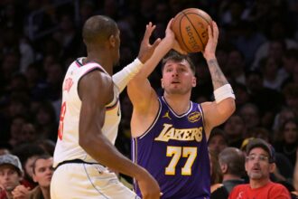 Nov 25, 2025; Los Angeles, California, USA; Los Angeles Lakers guard Luka Doncic (77) is defended by Los Angeles Clippers guard Kris Dunn (8) during the first half at Crypto.com Arena. Mandatory Credit: Jayne Kamin-Oncea-Imagn Images