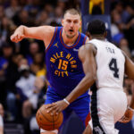 Nov 28, 2025; Denver, Colorado, USA; San Antonio Spurs guard De'Aaron Fox (4) controls the ball as Denver Nuggets center Nikola Jokic (15) guards in the second quarter at Ball Arena. Mandatory Credit: Isaiah J. Downing-Imagn Images