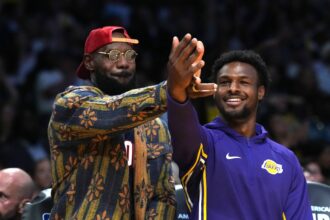 Los Angeles, California, USA; Los Angeles Lakers forward LeBron James (left) and son Bronny James watch from the bench in the second half against the Minnesota Timberwolves at Crypto.com Arena. Mandatory Credit: Kirby Lee-Imagn Images