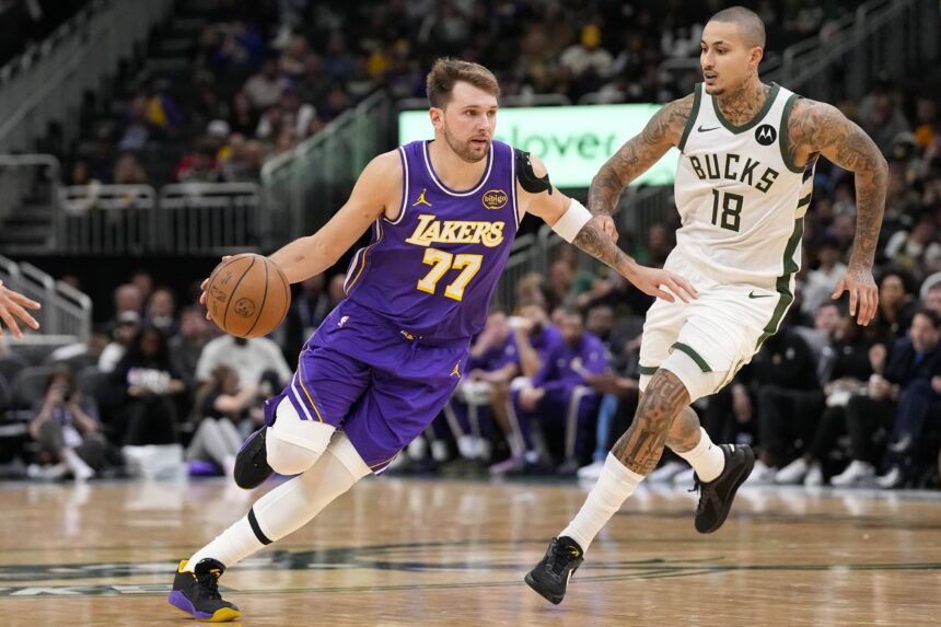 Milwaukee, Wisconsin, USA; Los Angeles Lakers guard Luka Doncic (77) drives towards the basket around Milwaukee Bucks forward Kyle Kuzma (18) during the third quarter at Fiserv Forum. Mandatory Credit: Jeff Hanisch-Imagn Images