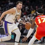Atlanta, Georgia, USA; Los Angeles Lakers guard Luka Doncic (77) dribbles against Atlanta Hawks forward Onyeka Okongwu (17) during the first half at State Farm Arena. Mandatory Credit: Dale Zanine-Imagn Images