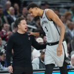 Dec 18, 2025; San Antonio, Texas, USA; San Antonio Spurs forward Victor Wembanyama (1) talks with head coach Mitch Johnson during the first half against the Washington Wizards at Frost Bank Center. Mandatory Credit: Scott Wachter-Imagn Images
