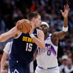 Dec 22, 2025; Denver, Colorado, USA; Denver Nuggets center Nikola Jokic (15) controls the ball as Utah Jazz forward Taylor Hendricks (0) guards in the second quarter at Ball Arena. Mandatory Credit: Isaiah J. Downing-Imagn Images