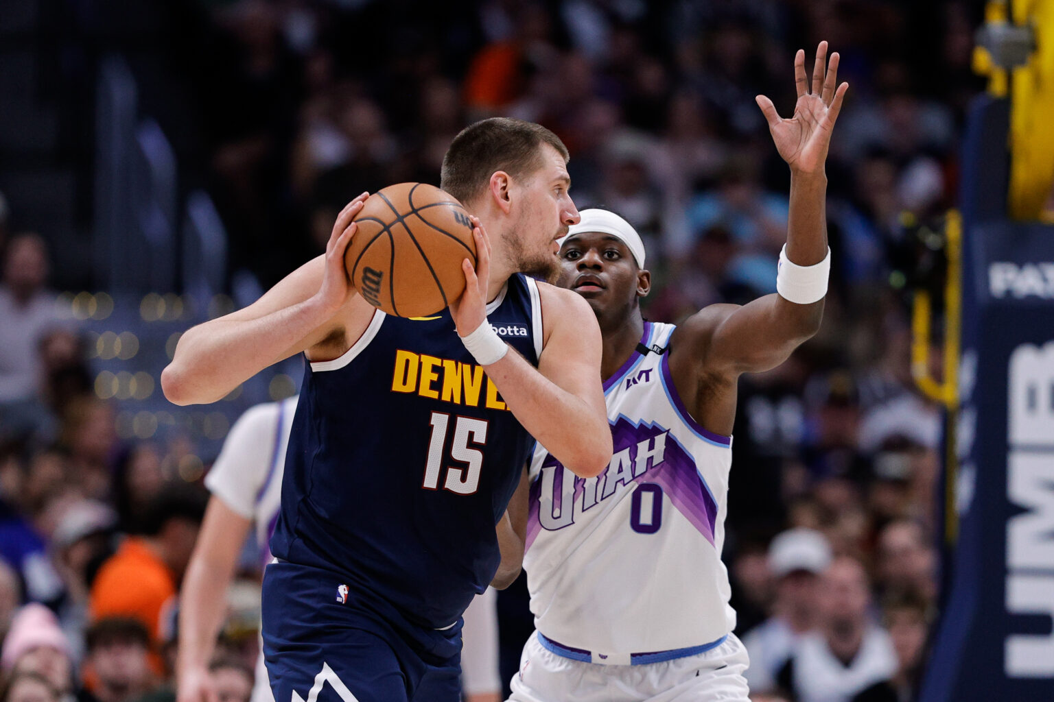 Dec 22, 2025; Denver, Colorado, USA; Denver Nuggets center Nikola Jokic (15) controls the ball as Utah Jazz forward Taylor Hendricks (0) guards in the second quarter at Ball Arena. Mandatory Credit: Isaiah J. Downing-Imagn Images