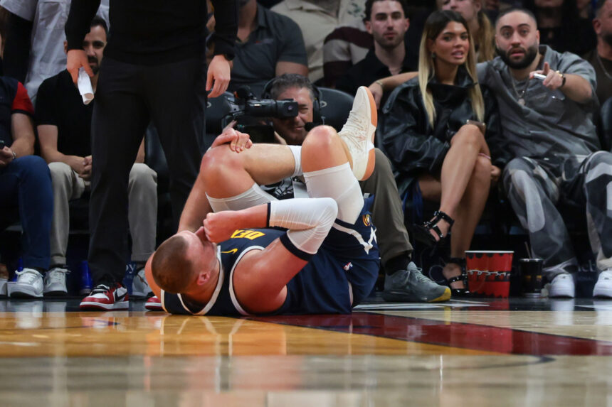 Dec 29, 2025; Miami, Florida, USA; Denver Nuggets center Nikola Jokic (15) holds his knee after an injury against the Miami Heat during the second quarter at Kaseya Center. Mandatory Credit: Sam Navarro-Imagn Images