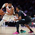 Nov 17, 2025; Miami, Florida, USA; New York Knicks center Karl-Anthony Towns (32) protects the basketball from Miami Heat guard Norman Powell (24) during the third quarter at Kaseya Center. Mandatory Credit: Sam Navarro-Imagn Images