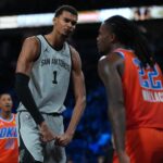 Dec 13, 2025; Las Vegas, Nevada, USA; San Antonio Spurs forward Victor Wembanyama (1) flexes in front of Oklahoma City Thunder guard Cason Wallace (22) during the third quarter at T-Mobile Arena. Mandatory Credit: Kirby Lee-Imagn Images