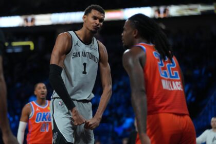 Dec 13, 2025; Las Vegas, Nevada, USA; San Antonio Spurs forward Victor Wembanyama (1) flexes in front of Oklahoma City Thunder guard Cason Wallace (22) during the third quarter at T-Mobile Arena. Mandatory Credit: Kirby Lee-Imagn Images