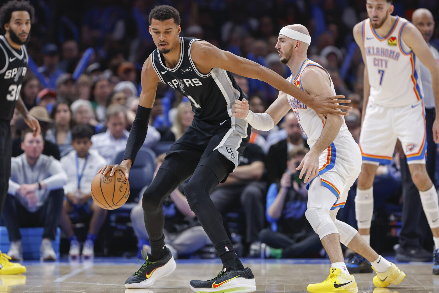 Dec 25, 2025; Oklahoma City, Oklahoma, USA; San Antonio Spurs forward Victor Wembanyama (1) moves the ball across the court against Oklahoma City Thunder guard Alex Caruso (9) during the second half at Paycom Center. Mandatory Credit: Alonzo Adams-Imagn Images