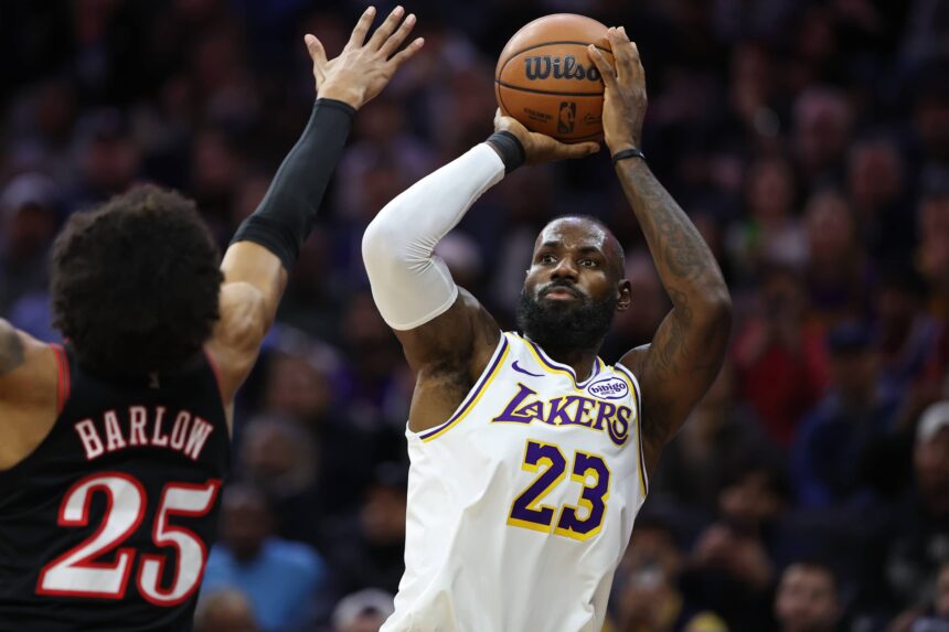 Philadelphia, Pennsylvania, USA; Los Angeles Lakers forward Lebron James (23) shoots past Philadelphia 76ers forward Dominick Barlow (25) during the first quarter at Xfinity Mobile Arena. Mandatory Credit: Bill Streicher-Imagn Images
