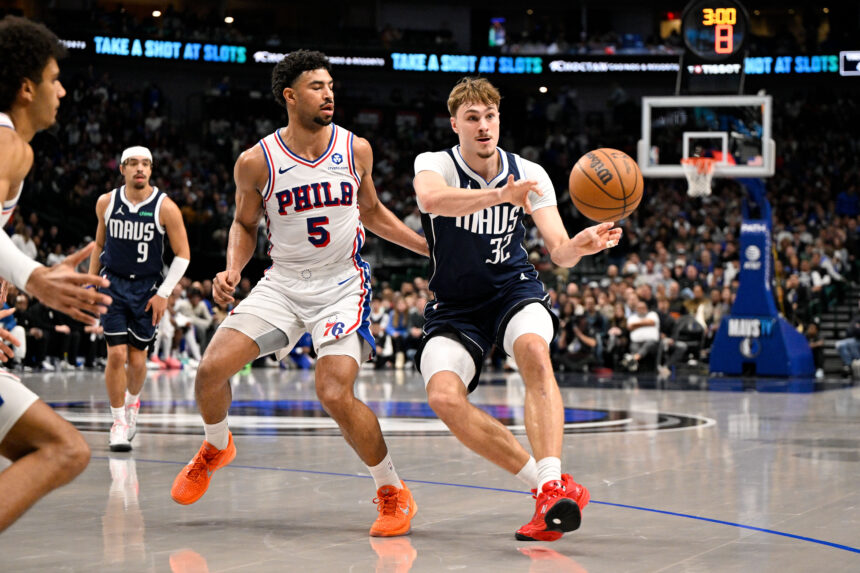 Jan 1, 2026; Dallas, Texas, USA; Dallas Mavericks forward Cooper Flagg (32) passes the ball by Philadelphia 76ers guard Quentin Grimes (5) during the second quarter at the American Airlines Center. Mandatory Credit: Jerome Miron-Imagn Images