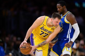 Oct 21, 2025; Los Angeles, California, USA; Los Angeles Lakers guard Luka Doncic (77) looks to drive against Golden State Warriors forward Jonathan Kuminga (1) during the second half at Crypto.com Arena. Mandatory Credit: William Liang-Imagn Images
