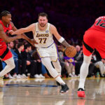 Jan 18, 2026; Los Angeles, California, USA; Los Angeles Lakers guard Luka Doncic (77) moves the ball against Toronto Raptors guard Ochai Agbaji (30) and forward Collin Murray-Boyles (12) during the first half at Crypto.com Arena. Mandatory Credit: Gary A. Vasquez-Imagn Images