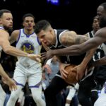 Dec 29, 2025; Brooklyn, New York, USA; Brooklyn Nets forward Michael Porter Jr. (17) grabs a rebound against Golden State Warriors guards Stephen Curry (30) and Will Richard (3) and forward Draymond Green (23) during the fourth quarter at Barclays Center. Mandatory Credit: Brad Penner-Imagn Images