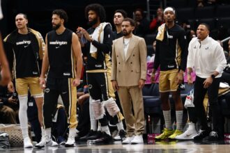 Jan 9, 2026; Washington, District of Columbia, USA; Newly acquired Washington Wizards guard Trae Young (M) looks on from the bench with teammates against the New Orleans Pelicans in the first half at Capital One Arena. Mandatory Credit: Geoff Burke-Imagn Images